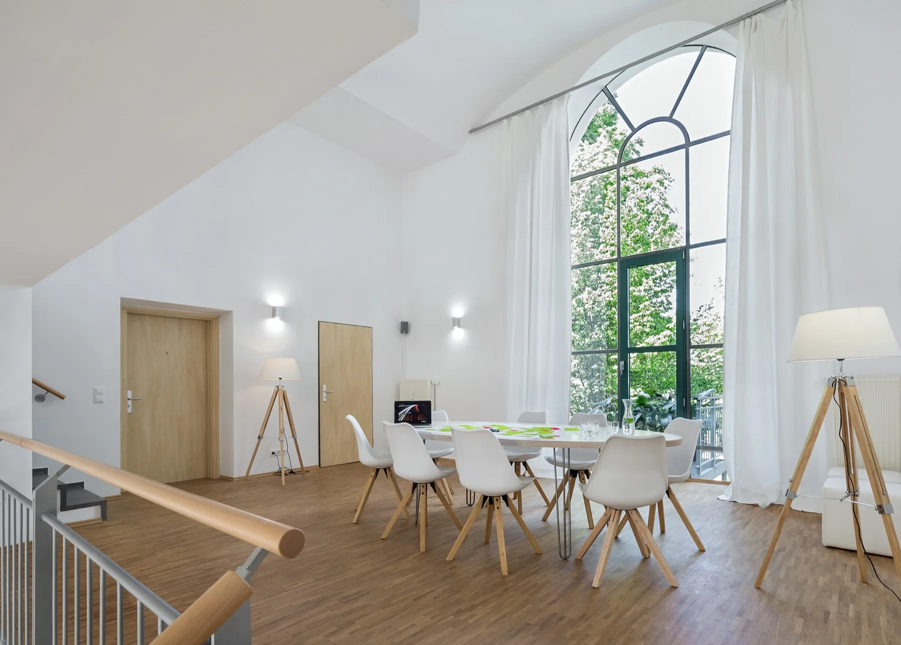 Lange Tafel im Loft 18 unter einem hohen Bogenfenster